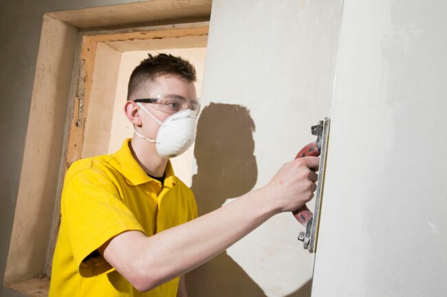 Student putting plaster on wall