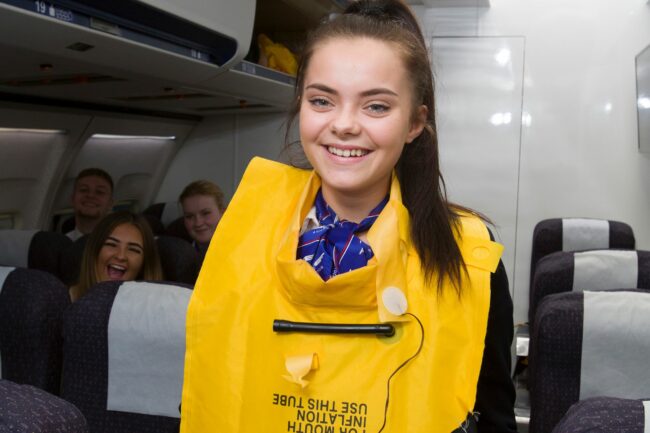 Student wearing lifejacket in simulated aircraft cabin