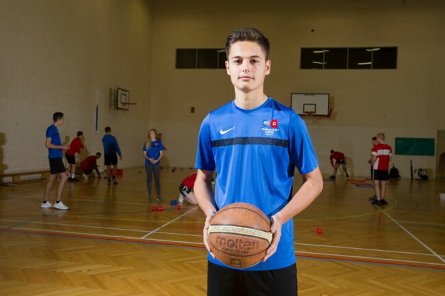 Sports student in sports hall holding basketball