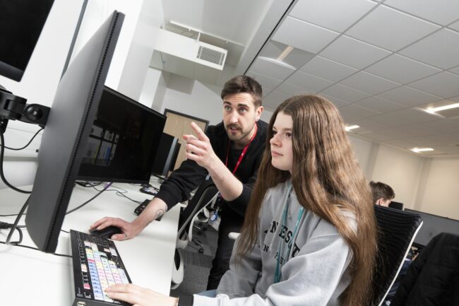 Tutor with student looking at computer