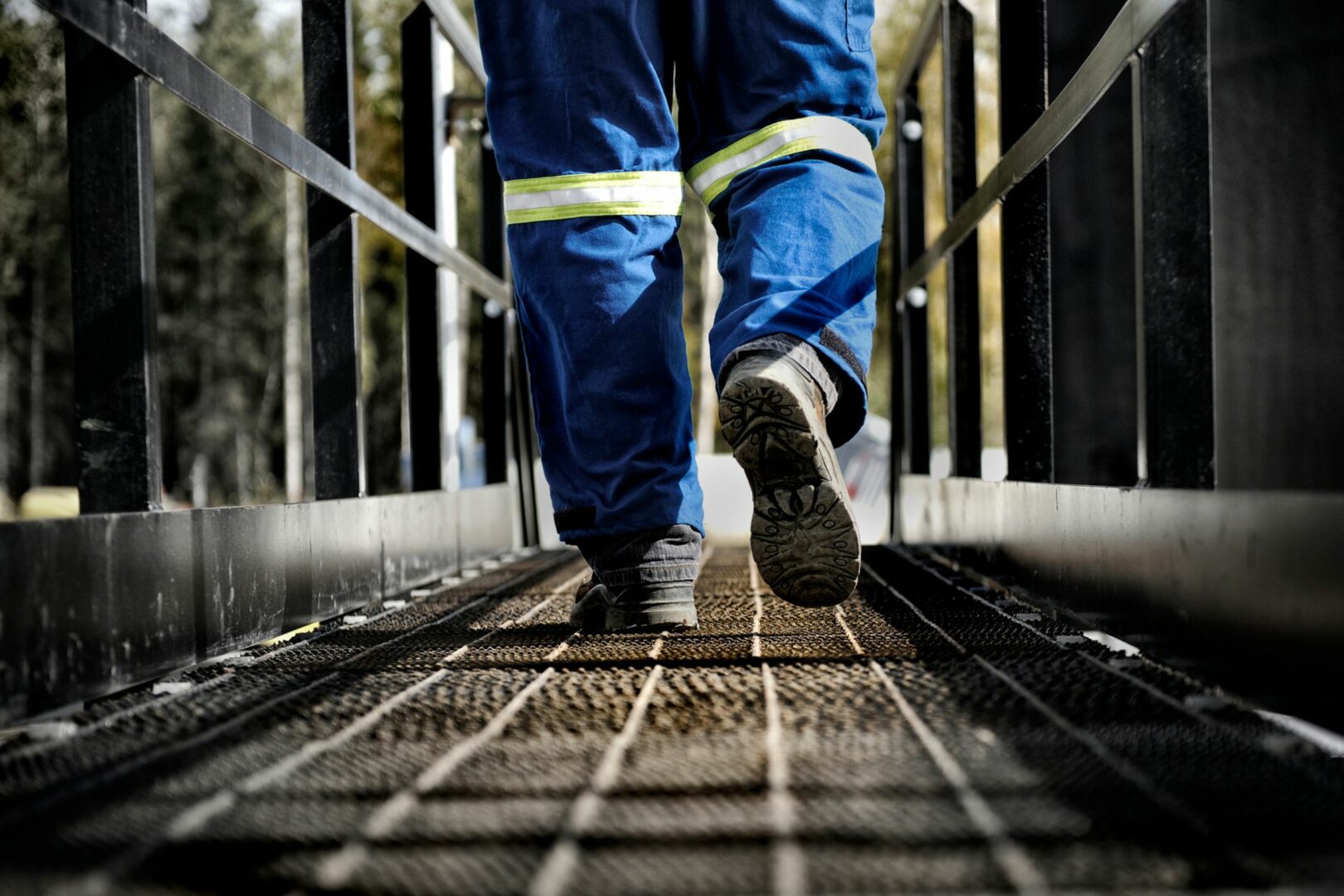 Legs in high-vis suite walking across steel bridge
