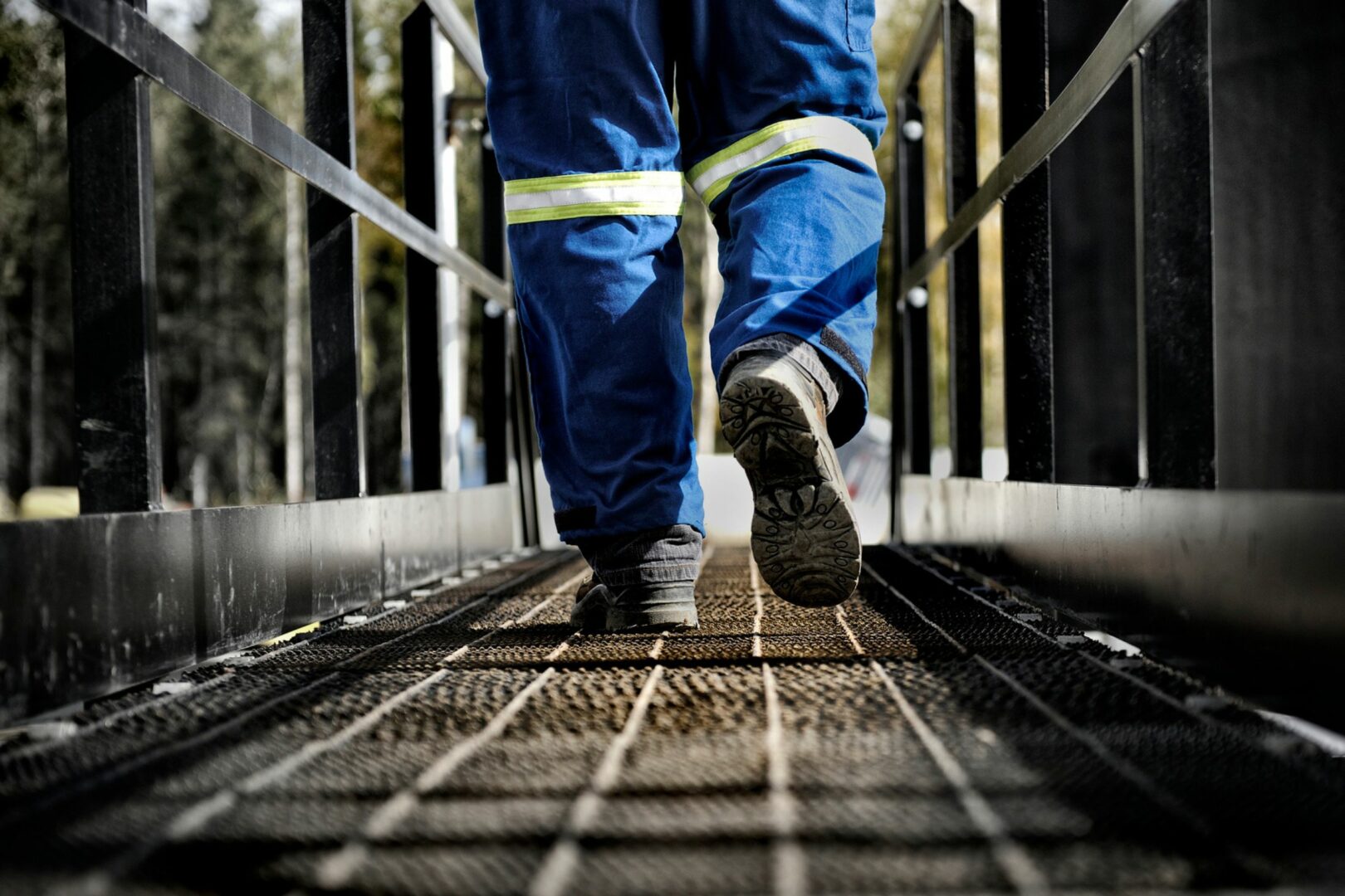 Legs in high-vis suite walking across steel bridge