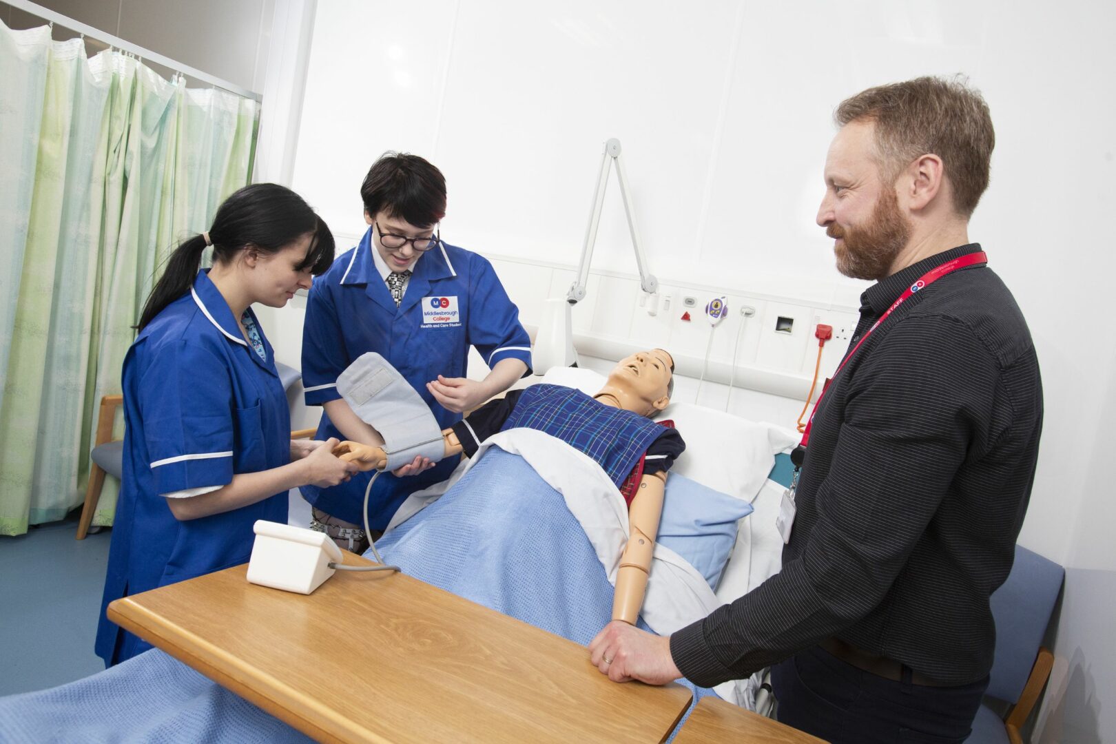 Students using blood pressure machine in health ward