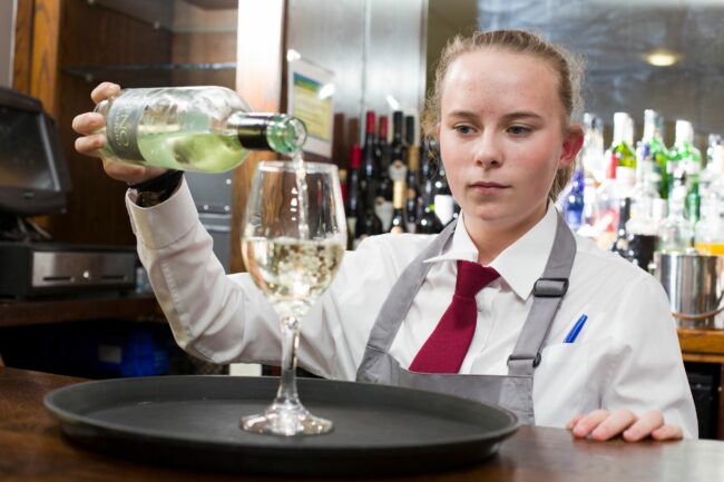 Hospitality student pouring wine into glass