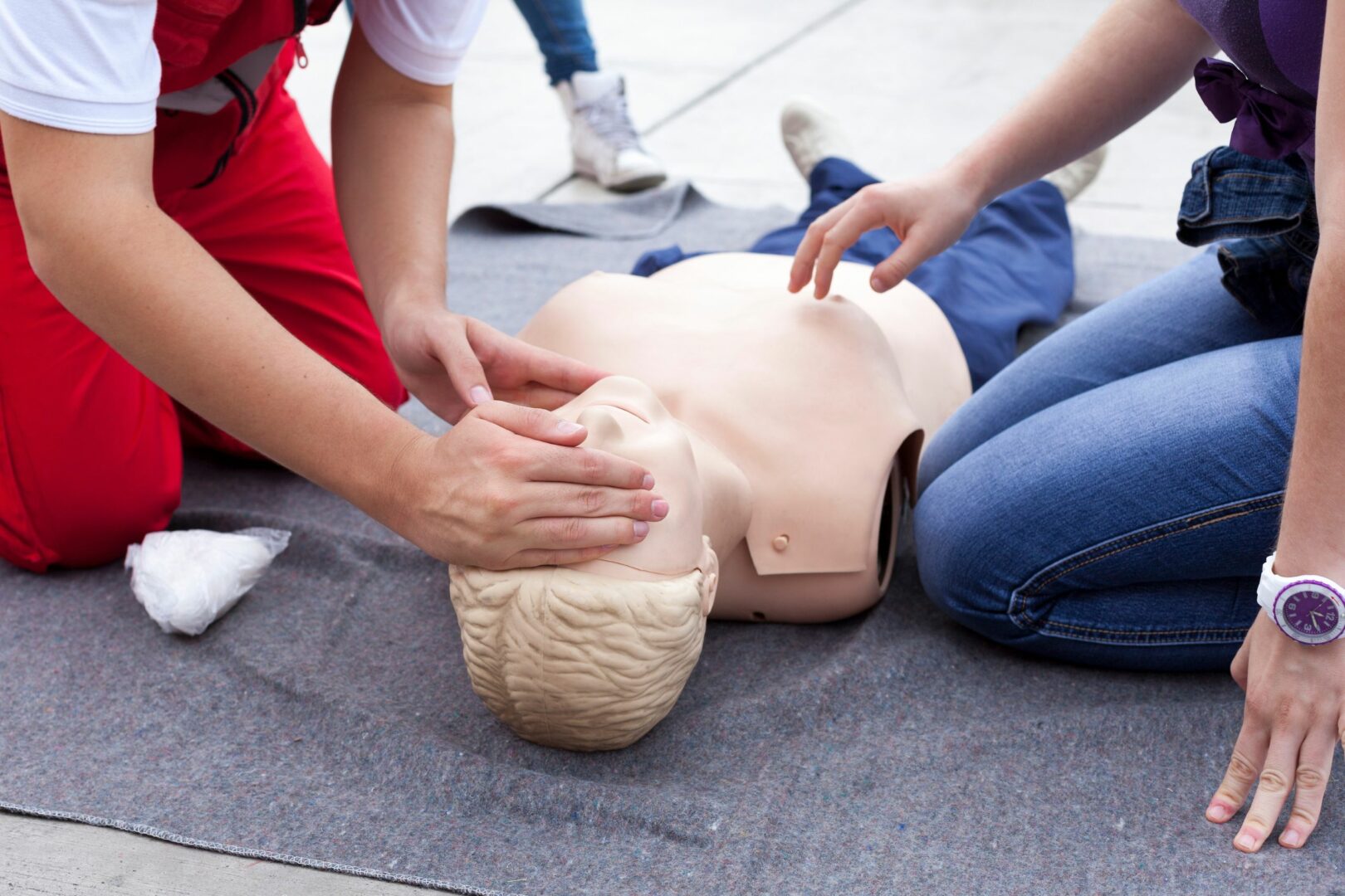 Two people practising CPR on first aid dummy