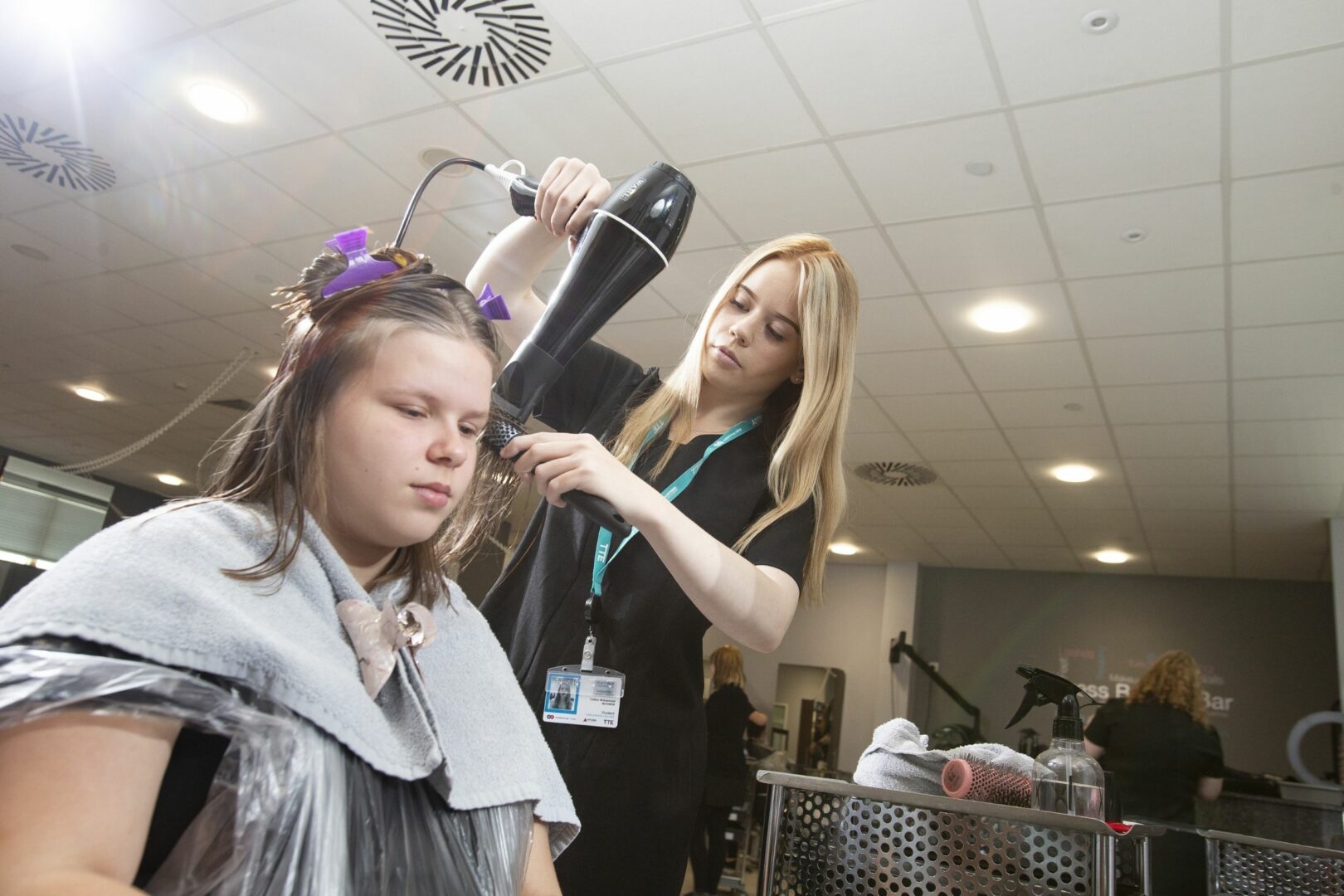 Hairdressing student drying hair
