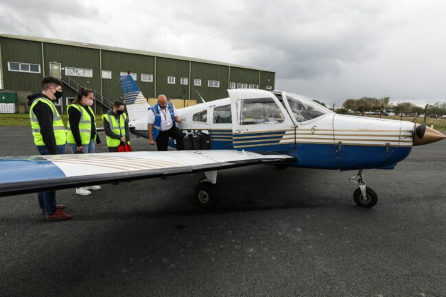 Students looking at small airplane