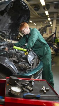 Motor vehicle student working on car engine