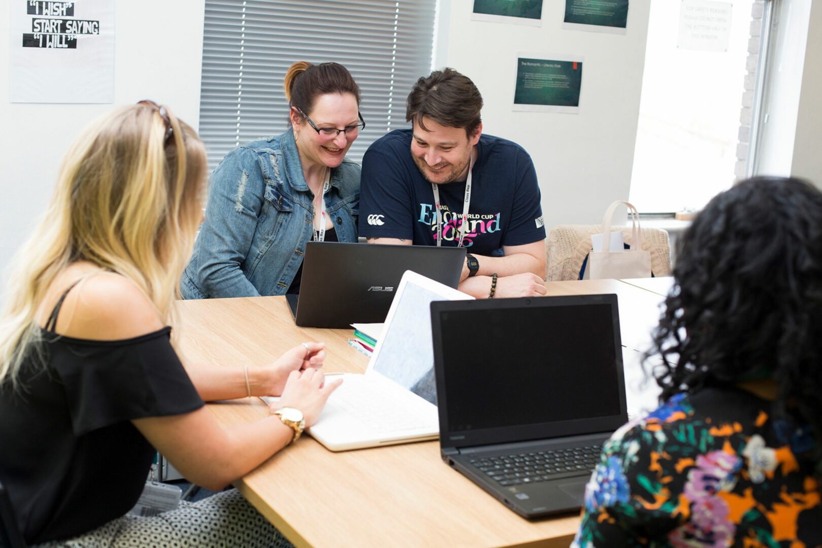 Adult learners sitting around desk on laptops