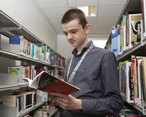 Business student reading book in library