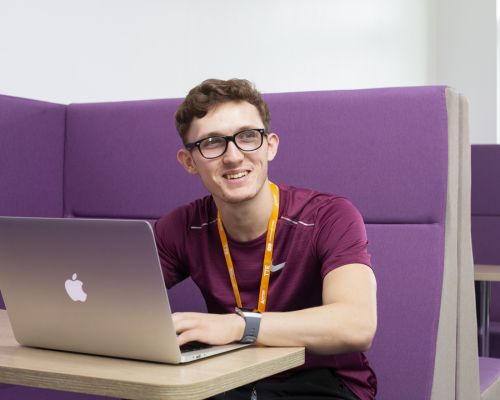 Higher education student working on laptop in purple booth