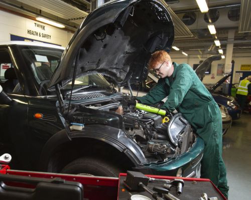 Motor vehicle student working on car engine