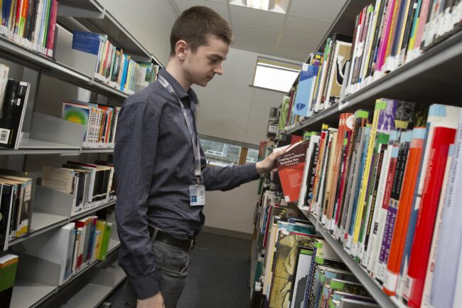 Business student looking at book in library