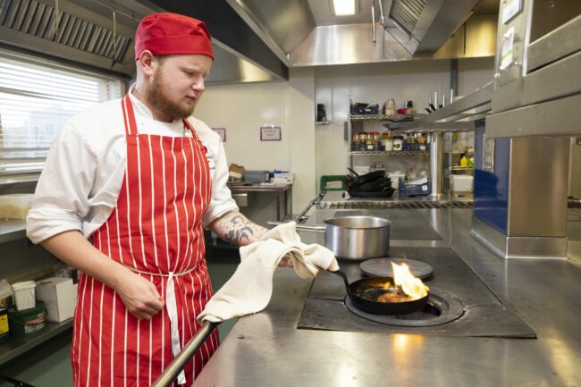 Catering student using frying pan