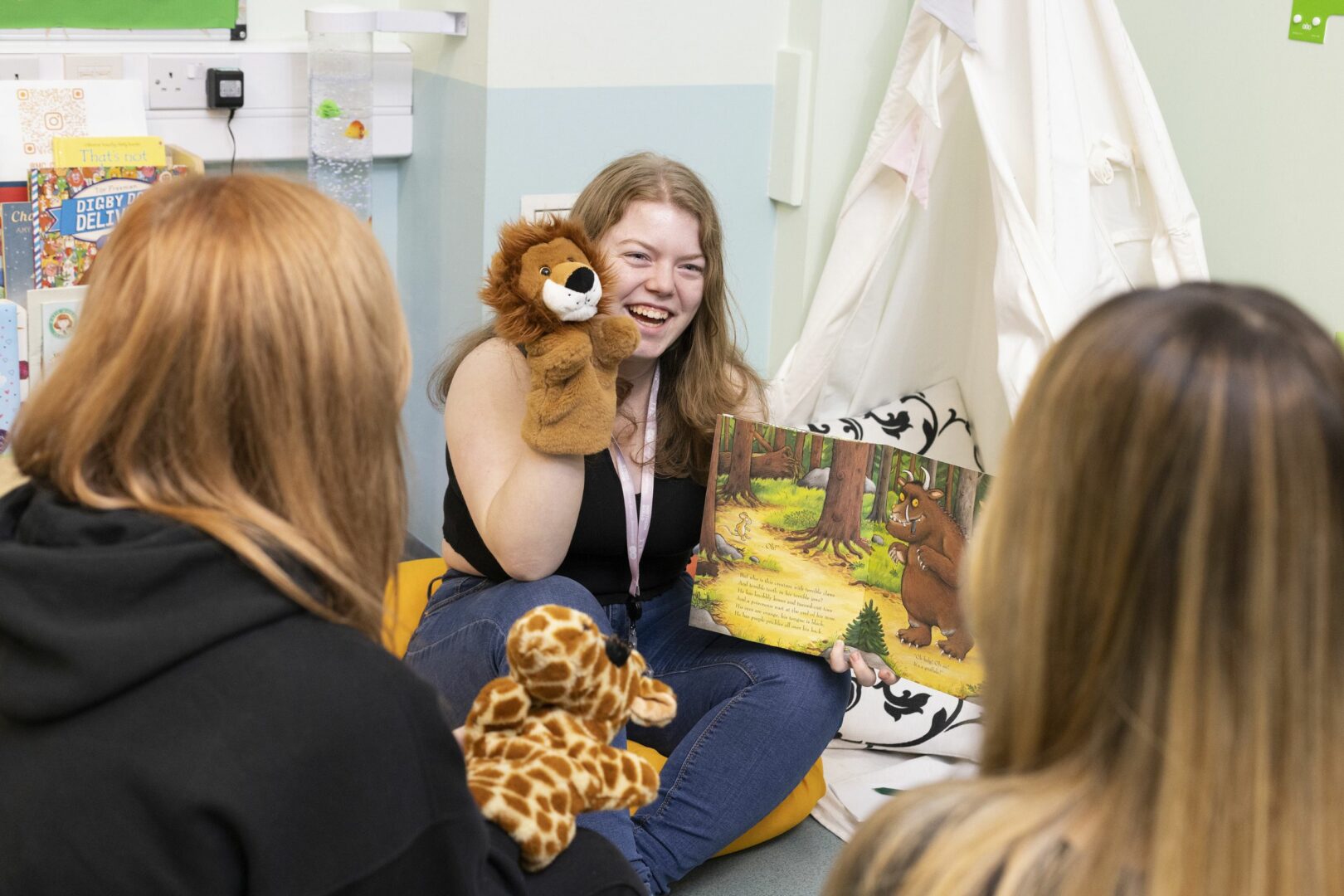 Childcare students reading book and using puppets