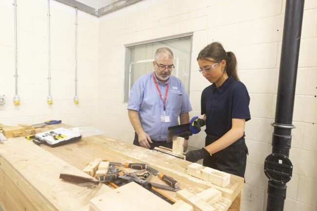 Construction tutor and student in wood workshop