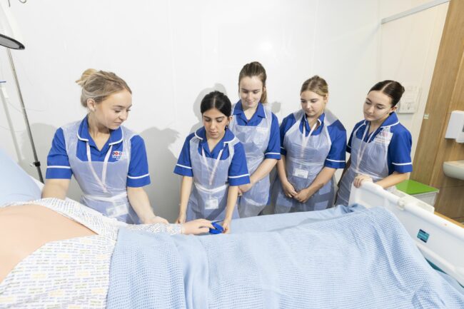 Health and care students practising on medical dummy