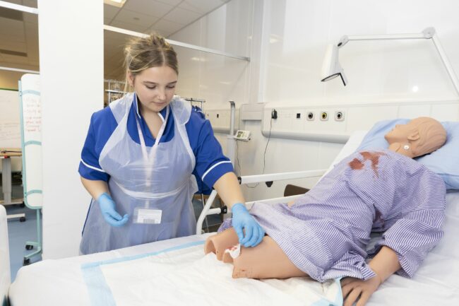 Health and care student practising on medical dummy