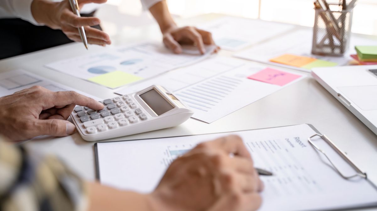 Hands using calculator and writing on clipboard