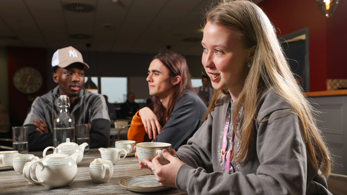 A student holding a coffee cup in Waterside Brasserie
